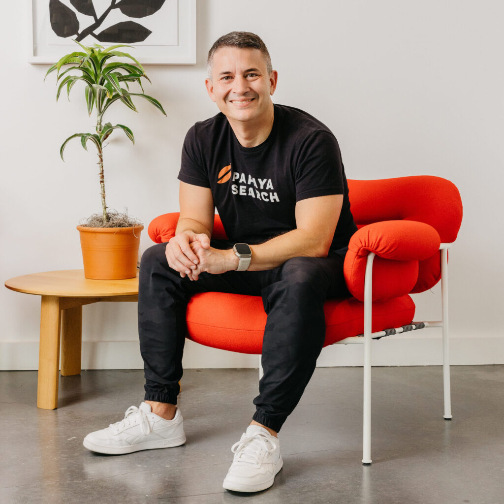 Smiling man seated on red chair indoors